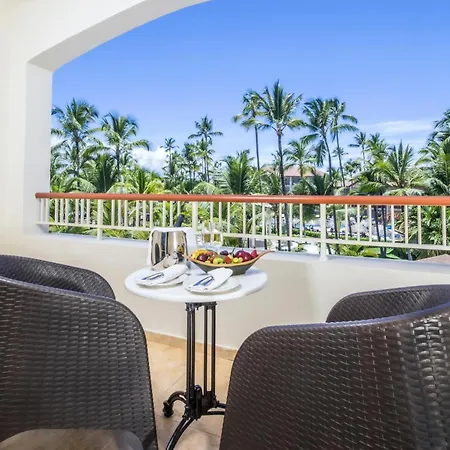 Majestic Colonial Punta Cana (Adults Only) Exterior photo This is a bright and inviting photo of a balcony overlooking a lush, tropical view.

In the foreground, there is a small, round white table set for a meal, featuring a bowl of colorful fruit and some plates with food. Two modern, dark brown woven wic